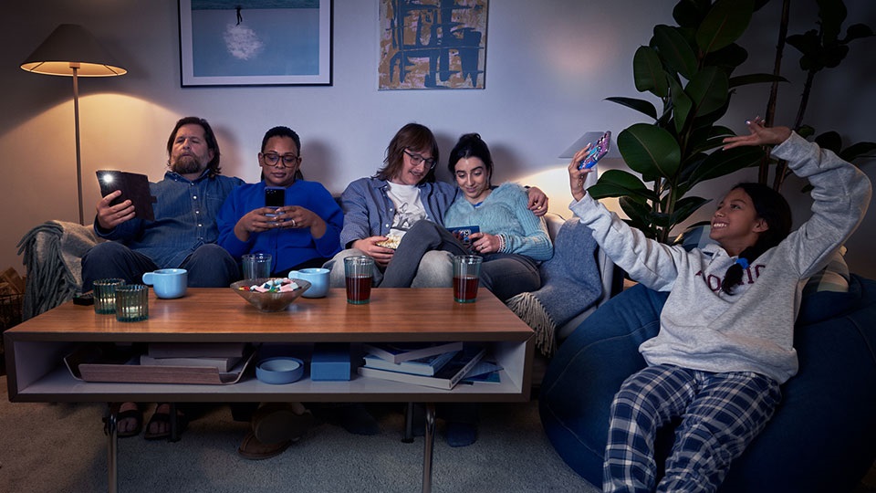 Familj sitter i tv-soffan men alla tittar på sina egna skärmar